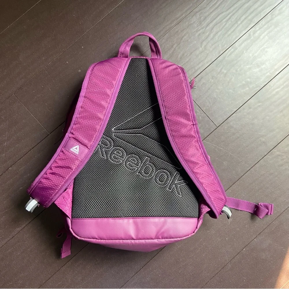 Purple Reebok book bag with tear right near strap